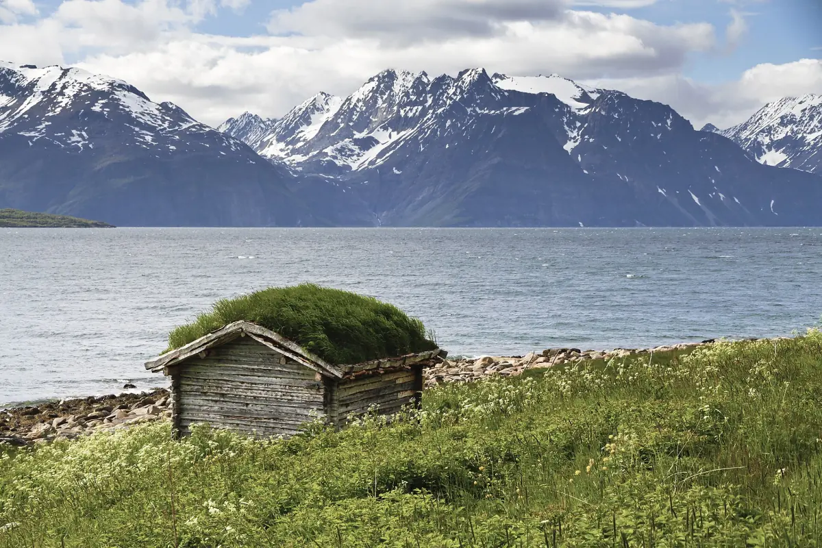 Eine Hütte mit Grasdach am Lyngenfjord vor den Lyngen-Alpen